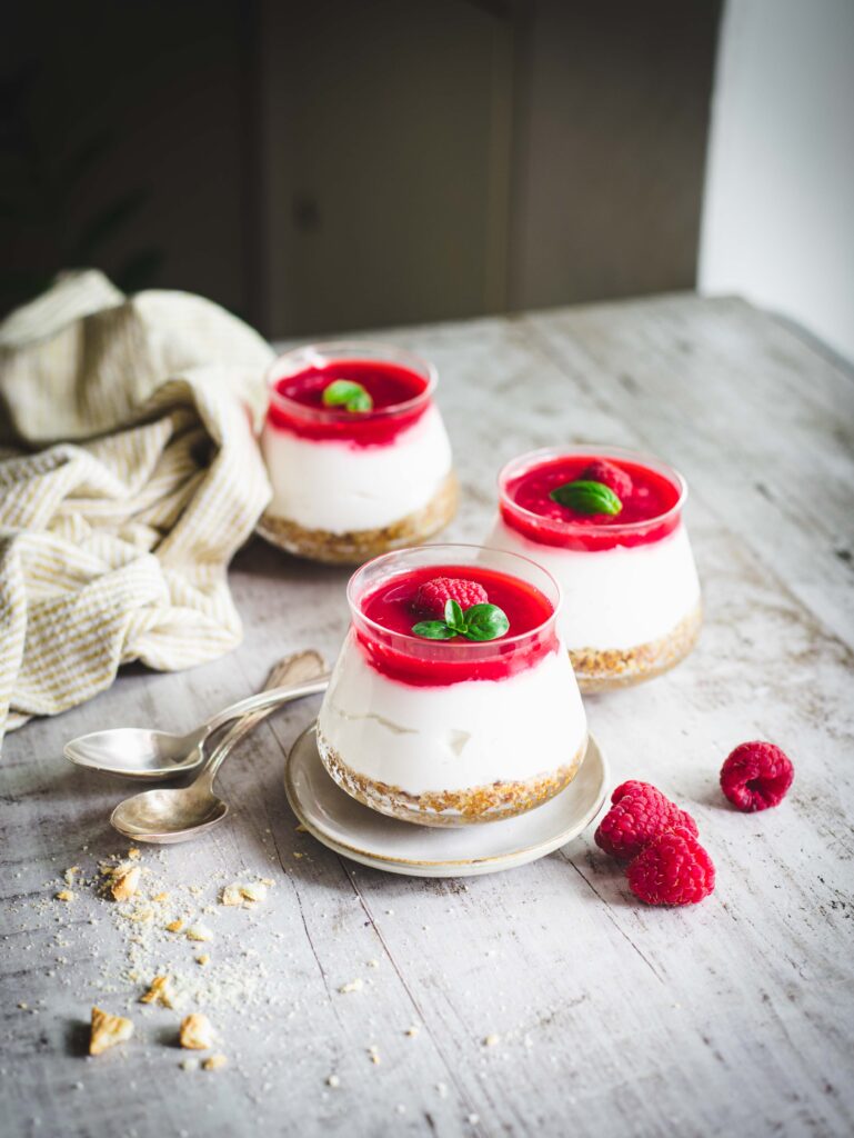 Vasetti di cheesecake vegana con yogurt e lamponi su tavolo