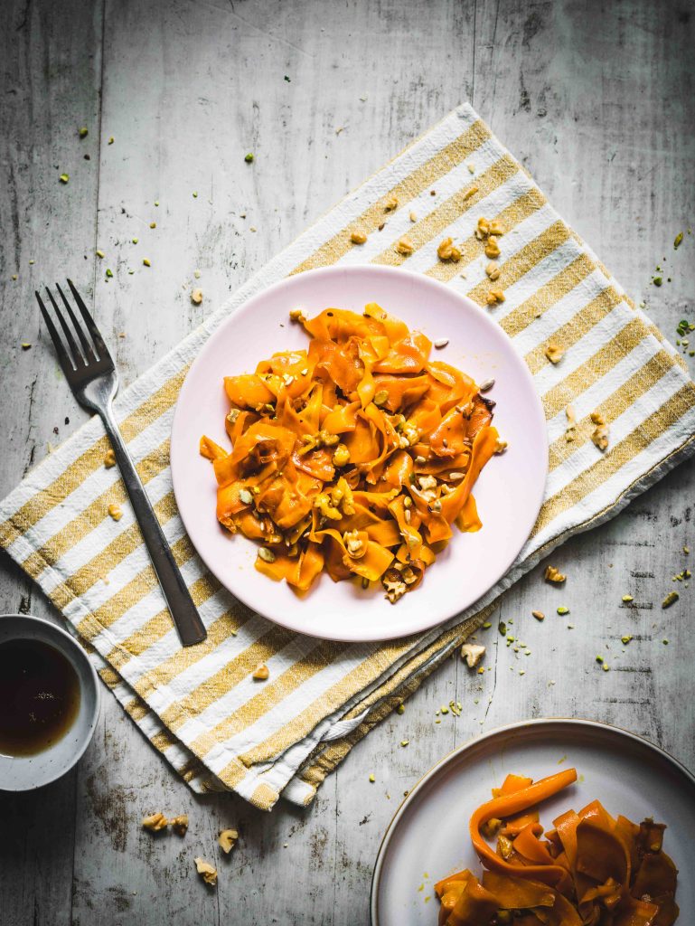 Carote in padella con sciroppo d'acero su piatto e canovaccio con forchetta